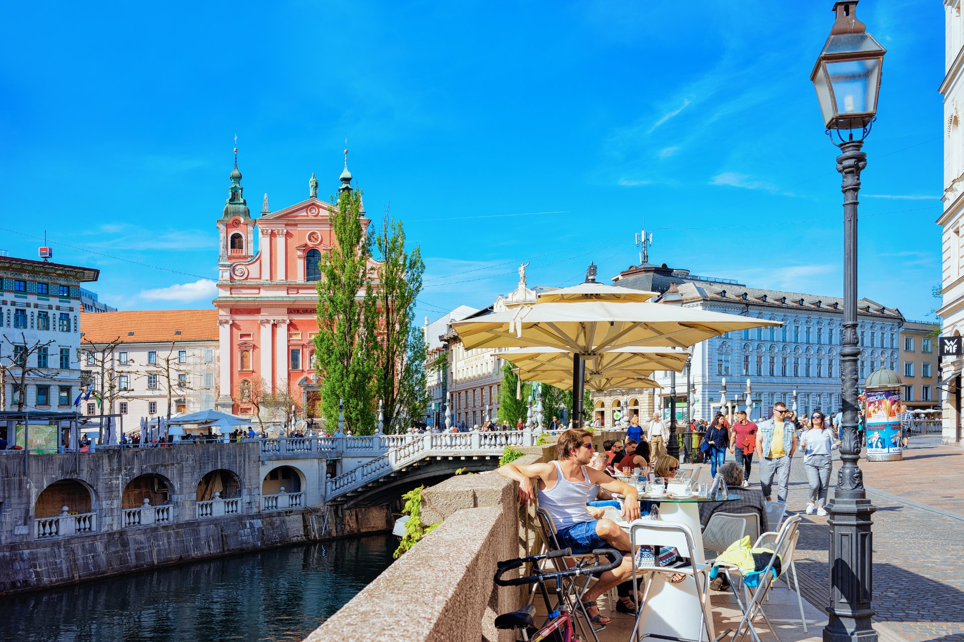 People at a sidewalk cafe on the Triple Bridge by the Ljubljanica River in Ljubljana